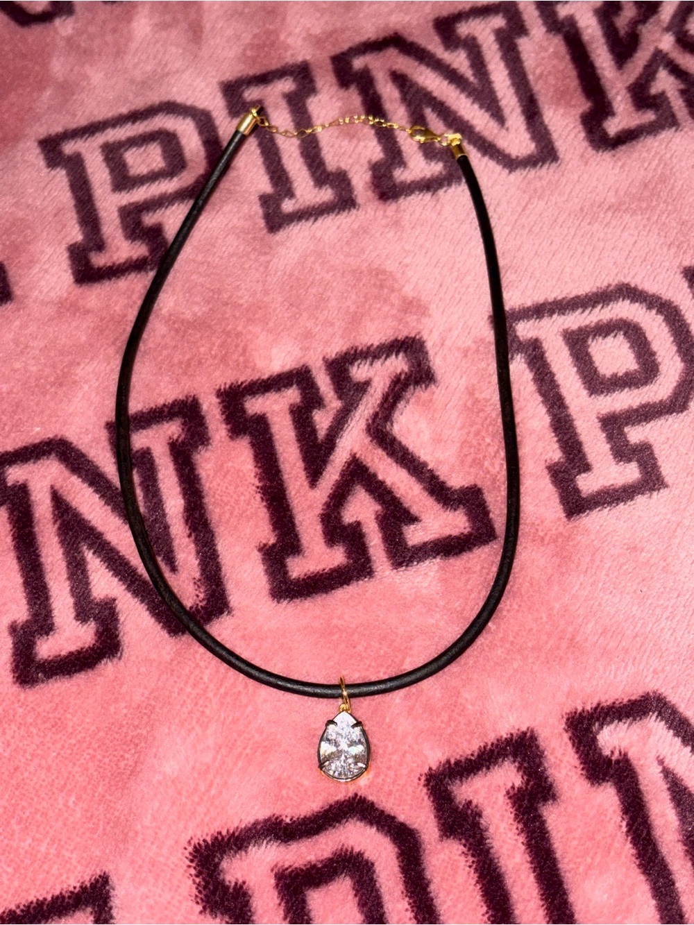 A pear-shaped stone is strung on a black rubber cord.